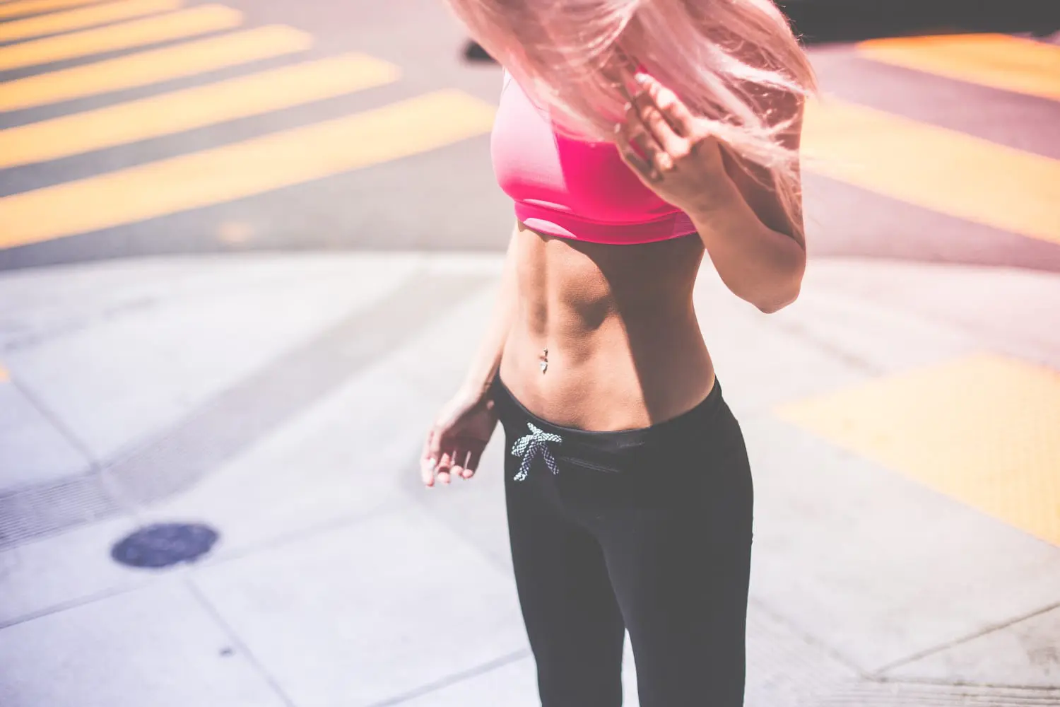 Woman standing on street corner looking down at her abs.
