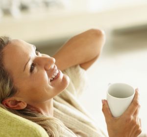 Smiling middle-aged woman with a cup of tea looking up