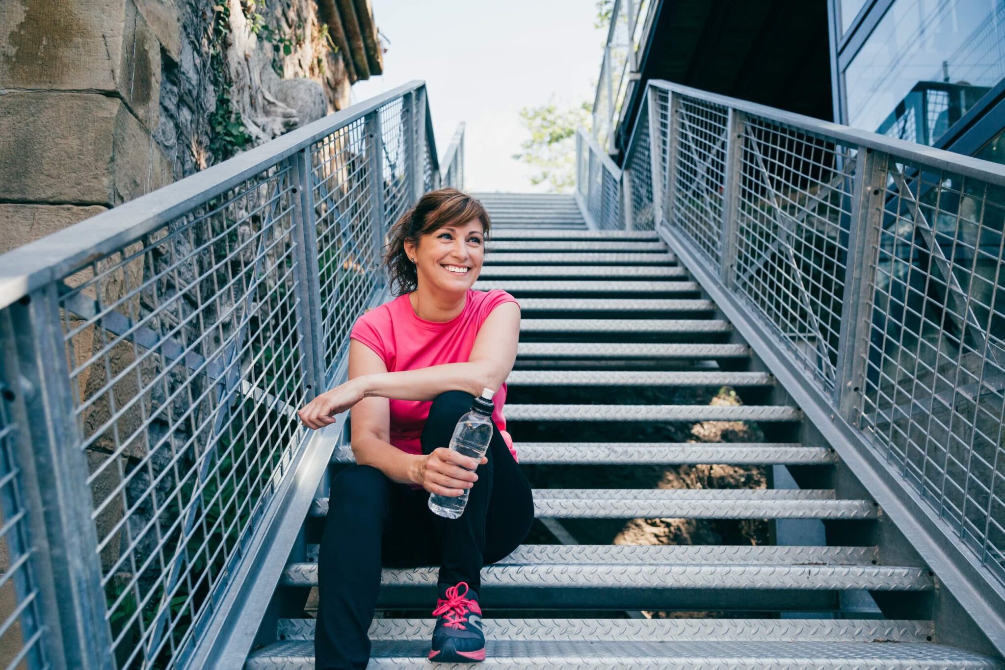 athletic middle aged woman resting on a staircase